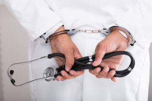 a doctor holding a stethoscope in handcuffs